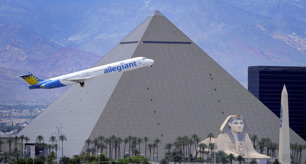 FILE - In this Thursday, May 9, 2013, file photo, an Allegiant Air jetliner flies by the Luxor Resort & Casino after taking off from McCarran International Airport in Las Vegas. (AP Photo/David Becker, File)