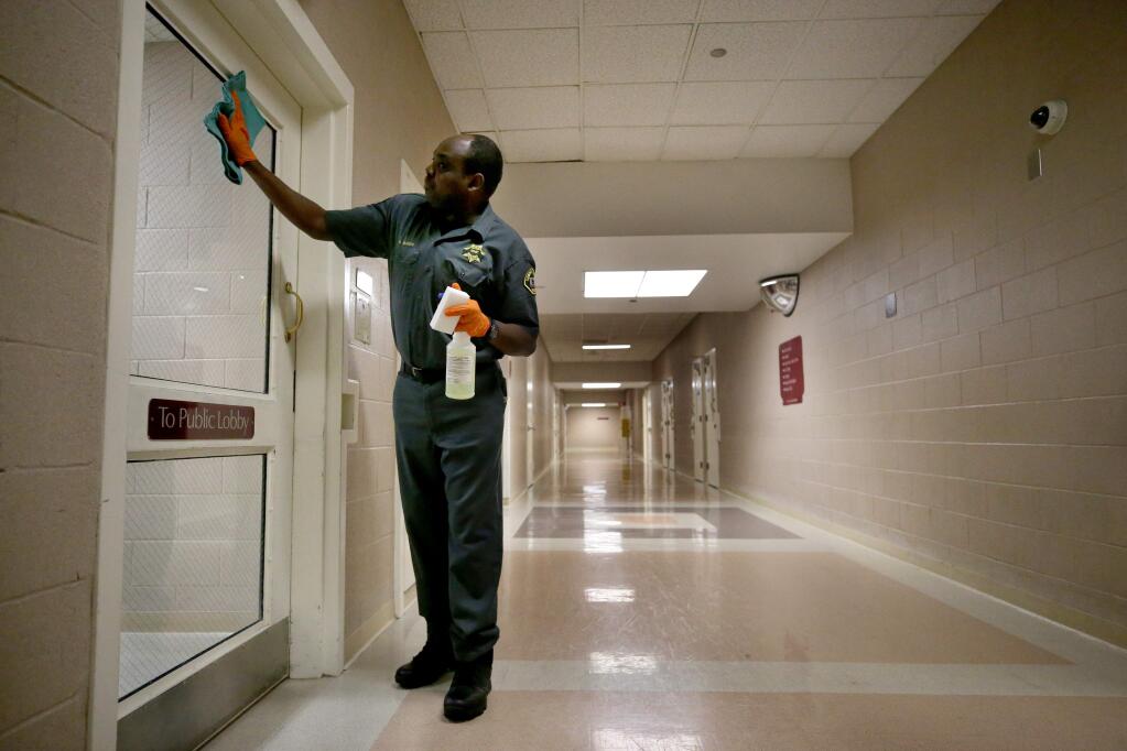 Janitor David Kilonzo sanitizes surfaces to try and prevent the spread of COVID-19 at the Sonoma County Main Adult Detention Facility in Santa Rosa on Sunday, March 15, 2020. (BETH SCHLANKER/ The Press Democrat)