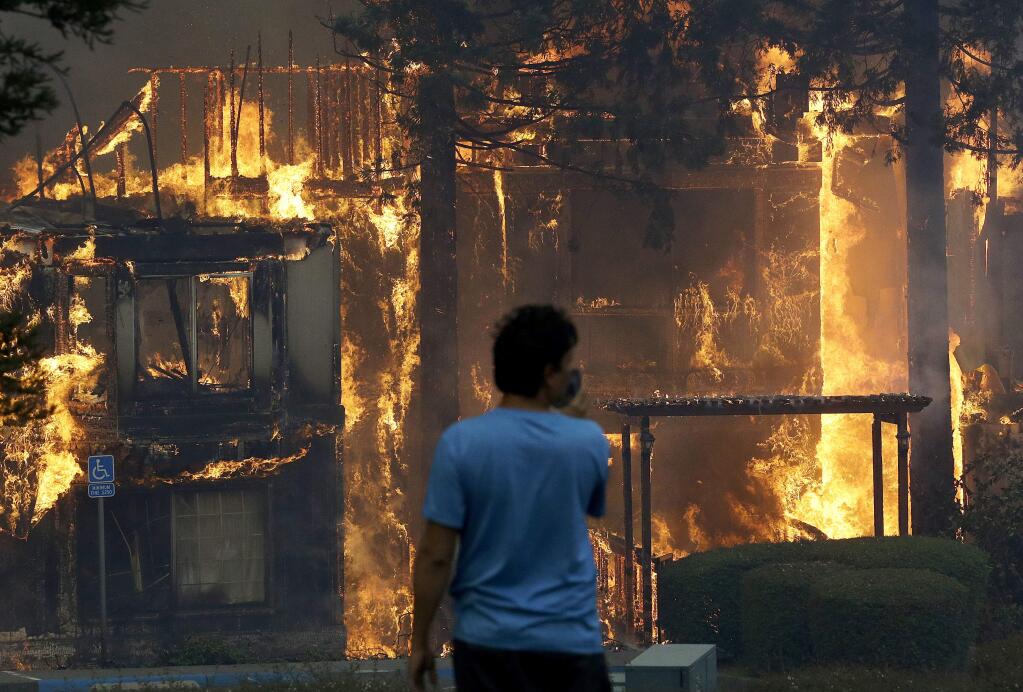 Rudy Habibe, from Puerto Rico, stands by the burning Hilton Sonoma Wine Country hotel, where he was a guest, in Santa Rosa, Calif., Monday, Oct. 9, 2017. Wildfires whipped by powerful winds swept through Northern California, sending residents on a headlong flight to safety through smoke and flames as homes burned. (AP Photo/Jeff Chiu)