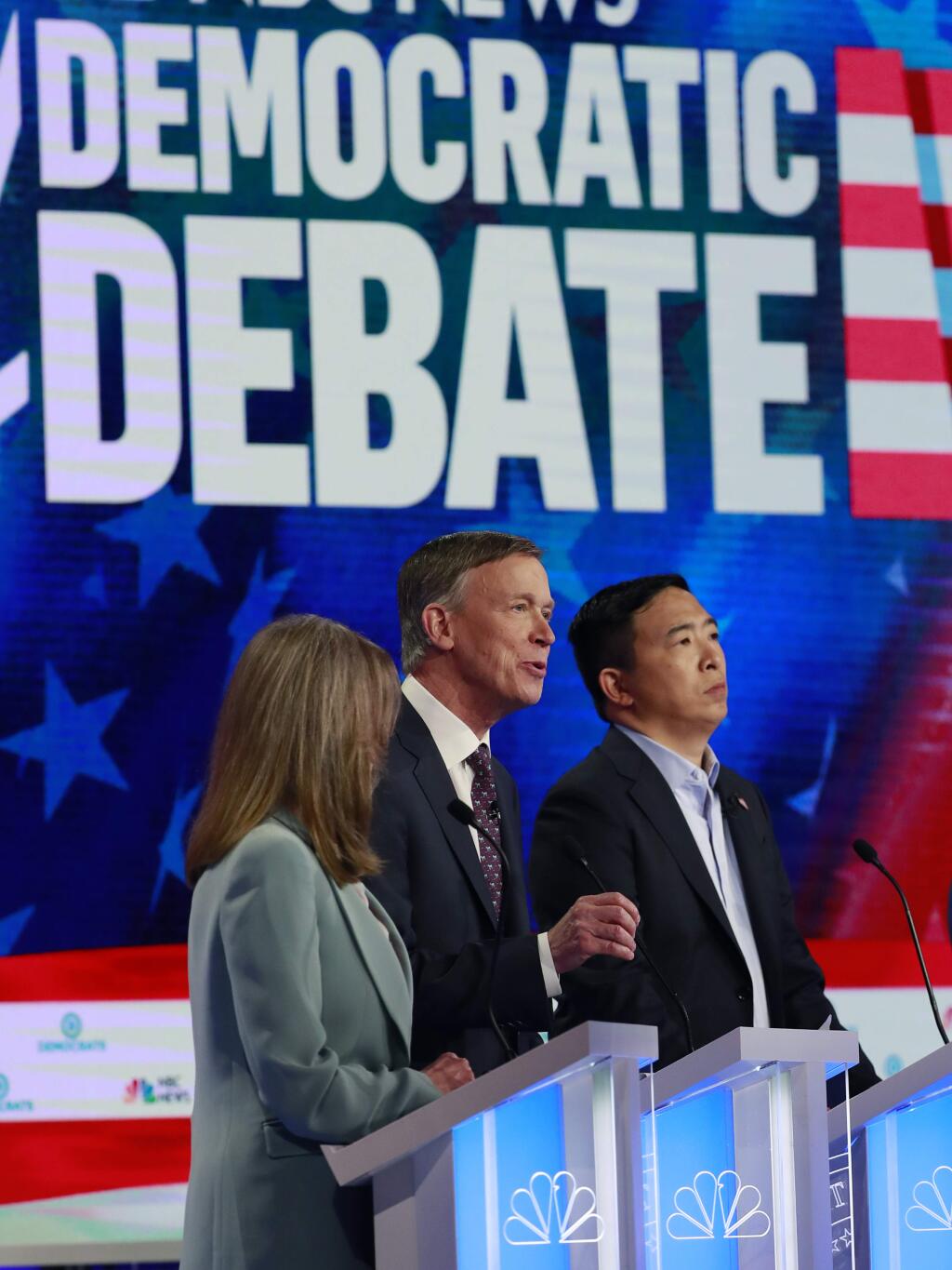 Democratic presidential candidate former Colorado Gov. John Hickenlooper, center, speaks during the Democratic primary debate hosted by NBC News at the Adrienne Arsht Center for the Performing Arts, Thursday, June 27, 2019, in Miami, as author Marianne Williamson and entrepreneur Andrew Yang listen. (AP Photo/Wilfredo Lee)