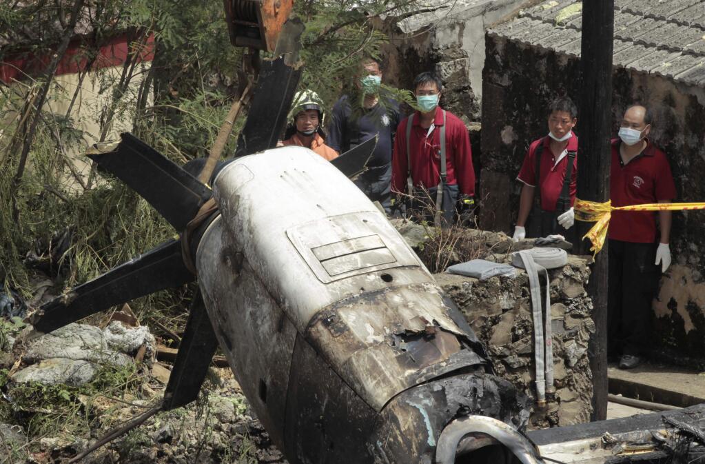 Emergency workers watch an engine lifted from the TransAsia Airways Flight GE222 crash site on the outlying Taiwan island of Penghu, Friday, July 25, 2014. (AP Photo/Wally Santana)