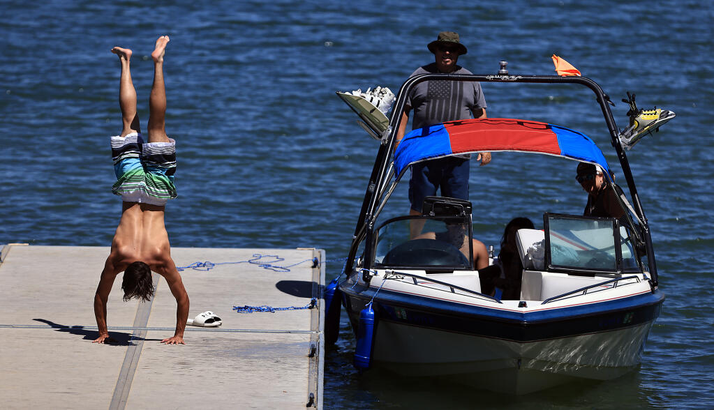 Esai Bermudez, 17, of Petaluma  vaults in to a handstand after a day of water skiing with family friend Kevin Labanowski and his family, Tuesday, July 11, 2023 at Lake Sonoma.  (Kent Porter / The Press Democrat) 2023