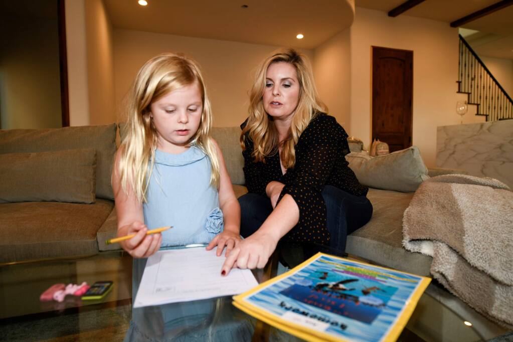 Kristy Militello, helps her daughter Ava with homework in the living room of their new home in San Diego. (Denis Poroy / For the Press Democrat)