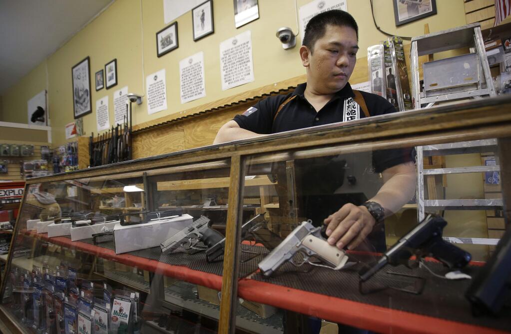 In this Wednesday, Sept. 30, 2015 photo, High Bridge Arms general manager Steve Alcairo reaches into a display case of handguns while being interviewed in San Francisco. High Bridge Arms, the last gun store in San Francisco, is scheduled to close on Oct. 31, 2015. (AP Photo/Jeff Chiu)