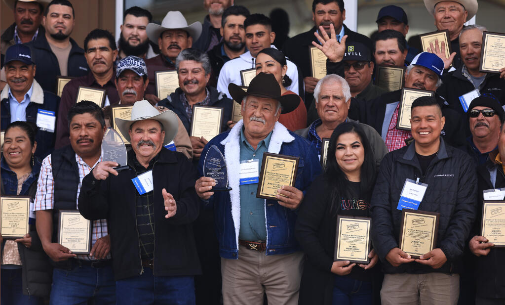 Jose Aceves, front row middle left,  joins Jose Guadalupe Nunez, right after the two took home the honors of Sonoma County Winegrowers Foundation Vineyard Employee of the Year, Saturday, Feb. 25, 2023, at the Sonoma County Fairgrounds.  Gathering with them for a group photo are employees of the month from various vineyard crews and wineries. (Kent Porter / The Press Democrat)