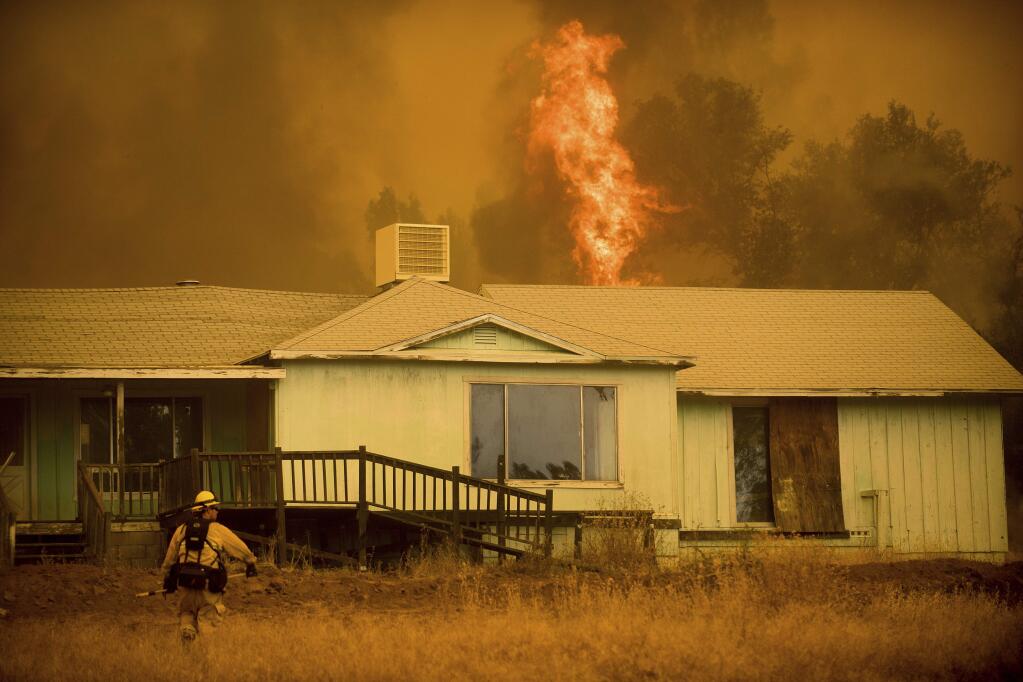 Flames rise behind a vacant house as a firefighter works to halt the Detwiler fire near Mariposa, Calif., on Wednesday, July 19, 2017. (AP Photo/Noah Berger)