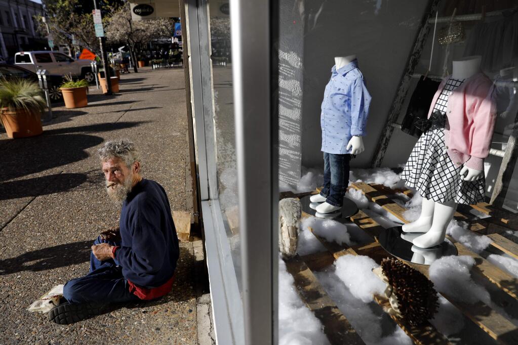 A homeless man smokes a cigar outside of Cupcake, a children's clothing store, in Santa Rosa, on Thursday, January 12, 2017. (BETH SCHLANKER/ The Press Democrat)
