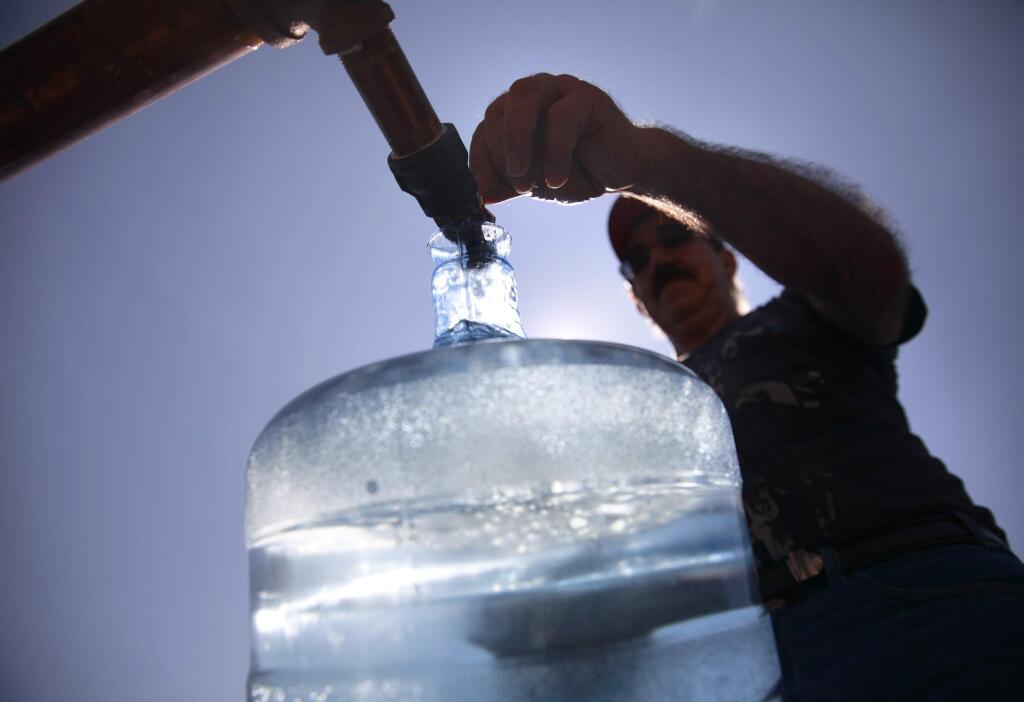 Alfredo Martin fills a jug of water at an emergency water fill station at the Las Flores Community Center in Napa, California, on Monday, August 25, 2014, one day after a magnitude 6.0 earthquake struck the region. (BETH SCHLANKER/ The Press Democrat)