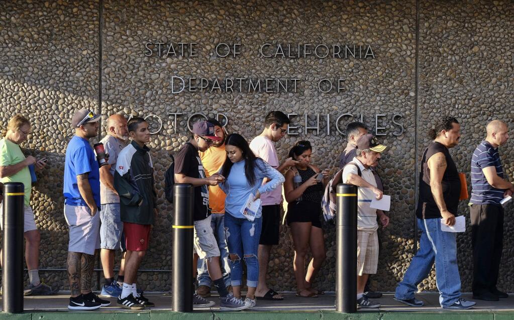 FILE - In this Tuesday, Aug. 7, 2018, file photo, people line up outside the offices of California's Department of Motor Vehicles, DMV Van Nuys offices in Los Angeles. Lawmakers can avoid the long lines plaguing California's Department of Motor Vehicles offices by visiting an office near the Capitol not open to the public. (AP Photo/Richard Vogel, File)