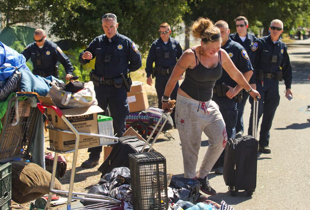 Santa Rosa Police officers wait for a homeless woman to take what she can from her site as they close the large encampment along the Joe Rodota Trail west of Dutton Ave. in Santa Rosa. (photo by John Burgess/The Press Democrat)
