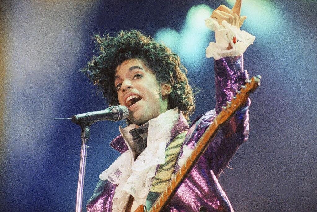 FILE - In this Feb. 18, 1985 file photo, Prince performs at the Forum in Inglewood, Calif. A pair of record labels announced Friday, April 28, 2017, that a remastered edition of Prince's landmark 1984 album “Purple Rain” will be released on June 23, 2017. The labels say Prince oversaw the remastering process in 2015 and the “Purple Rain Deluxe” will include six previously unreleased songs by the late singer-songwriter, who died one year ago. (AP Photo/Liu Heung Shing, File)