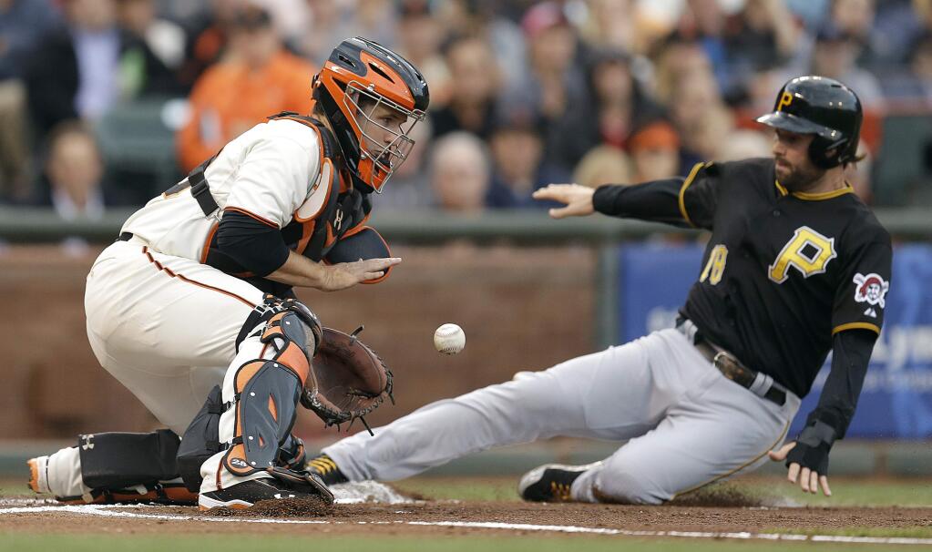 Pittsburgh Pirates' Neil Walker, right, slides to score as San Francisco Giants catcher Buster Posey waits for the ball in the first inning of a baseball game Monday, July 28, 2014, in San Francisco. Walker scored on a sacrifice fly by Pittsburgh's Gregory Polanco(AP Photo/Ben Margot)
