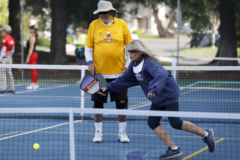 Diana Brant with the guidance of coach Bill Petrie, rear, takes part in a free pickleball clinic at Sunrise Park in Rohnert Park, Calif., on Thursday, June 2, 2022. (BETH SCHLANKER/ The Press Democrat)