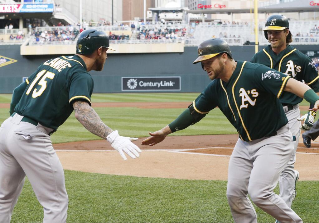 Oakland Athletics Stephen Vogt, right, is greeted by Brett Lawrie, left, after his grand slam off Minnesota Twins pitcher Phil Hughes in the first inning of a baseball game, Monday, May 4, 2015, in Minneapolis. (AP Photo/Jim Mone)