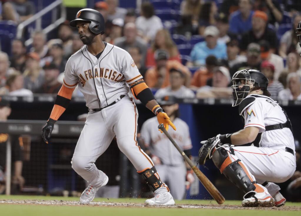 San Francisco Giants' Andrew McCutchen, left watches after hitting a RBI double to score Gorkys Hernandez during the fifth inning of a baseball game against the Miami Marlins, Monday, June 11, 2018, in Miami. At right is Miami Marlins catcher J.T. Realmuto. (AP Photo/Lynne Sladky)
