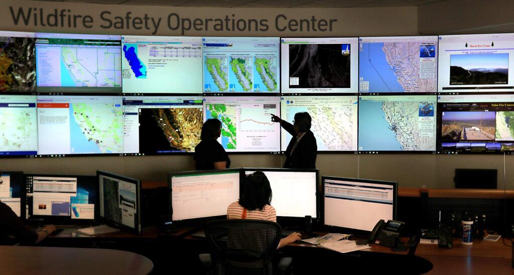 Evermary Hickey, PG&E's director of emergency preparedness and response, left and supervisor Diana Herr look over the one of the 16 monitors displaying weather information around central and northern California, Tuesday, May 8, 2018 in their new wildfire safety operations center at the Pacific Gas and Electric headquarters in San Francisco. (Kent Porter / The Press Democrat) 2018
