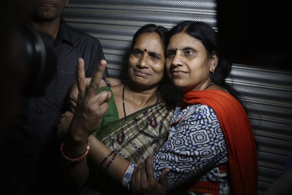 Asha Devi, left, mother of the victim of the fatal 2012 gang rape on a moving bus, displays a victory sign with her sister after the rapists of her daughter were hanged, in New Delhi, India, Friday, March 20, 2020. Four men were sentenced to capital punishment for the 2012 gang-rape of a 23-year-old physiotherapy student on a moving bus in New Delhi have been executed. (AP Photo/Altaf Qadri)