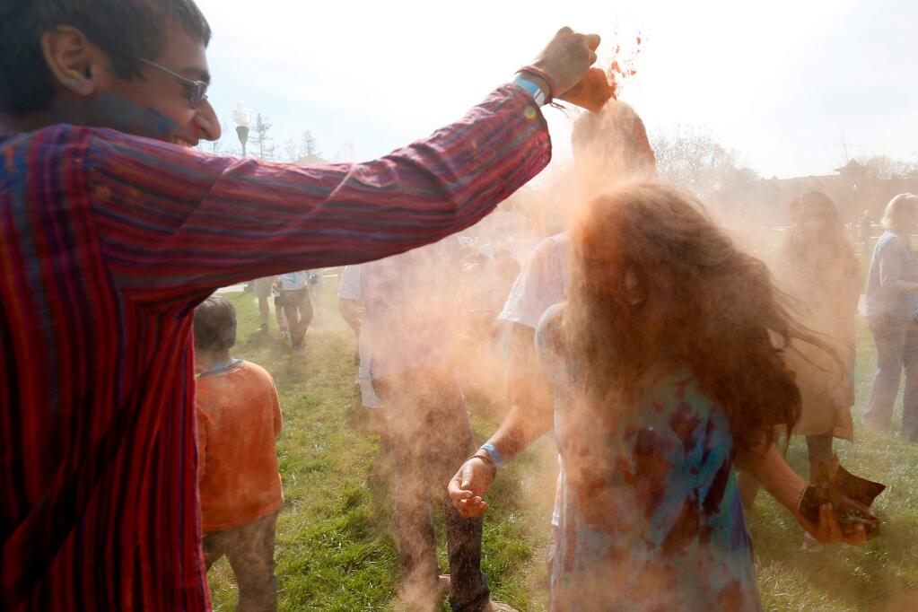 Jai Dhiman, 16, left, shakes colored powder all over his older sister Surbhi, 20, as their brother Shrey, 16, keeps Surbhi from running away during Holi, a Hindu festival of colors celebrating the arrival of spring, at the Windsor Town Green in Windsor, California, on Saturday, March 11, 2017. (Alvin Jornada / The Press Democrat)