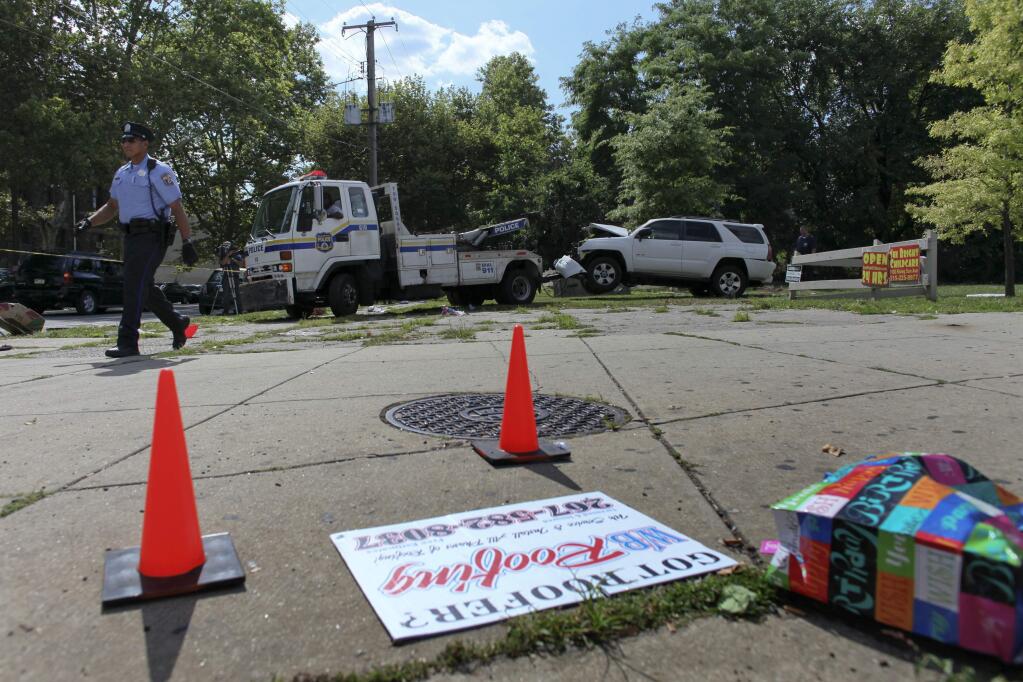 Police tow a heavily damaged SUV from the scene of a fatal accident in North Philadelphia, Friday July 25, 2014. Three children were killed when a hijacked car lost control and hit a group of people near a fruit stand, according to police. (AP Photo/ Joseph Kaczmarek)