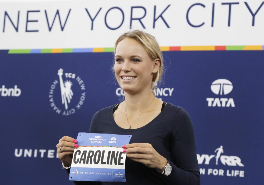 Professional tennis player Caroline Wozniacki poses with her runner's bib during a news conference, Wednesday, Oct. 29, 2014, in New York. The Danish tennis star, formerly top-ranked in the world, will run the New York City Marathon, Sunday, Nov. 2, to raise funds for the New York Road Runners Team for Kids charity, which promotes youth running. (AP Photo/Mark Lennihan)