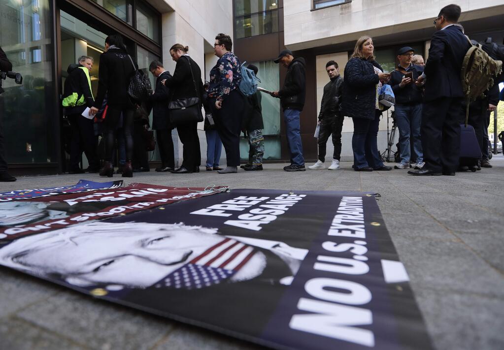 A poster lays on the pavement as supporters and journalists queue at the entrance of Westminster Magistrates Court in London, Thursday, May 2, 2019, where WikiLeaks founder Julian Assange is expected to appear by video link from prison. Assange is facing a court hearing over a U.S. request to extradite him for alleged computer hacking. (AP Photo/Frank Augstein)