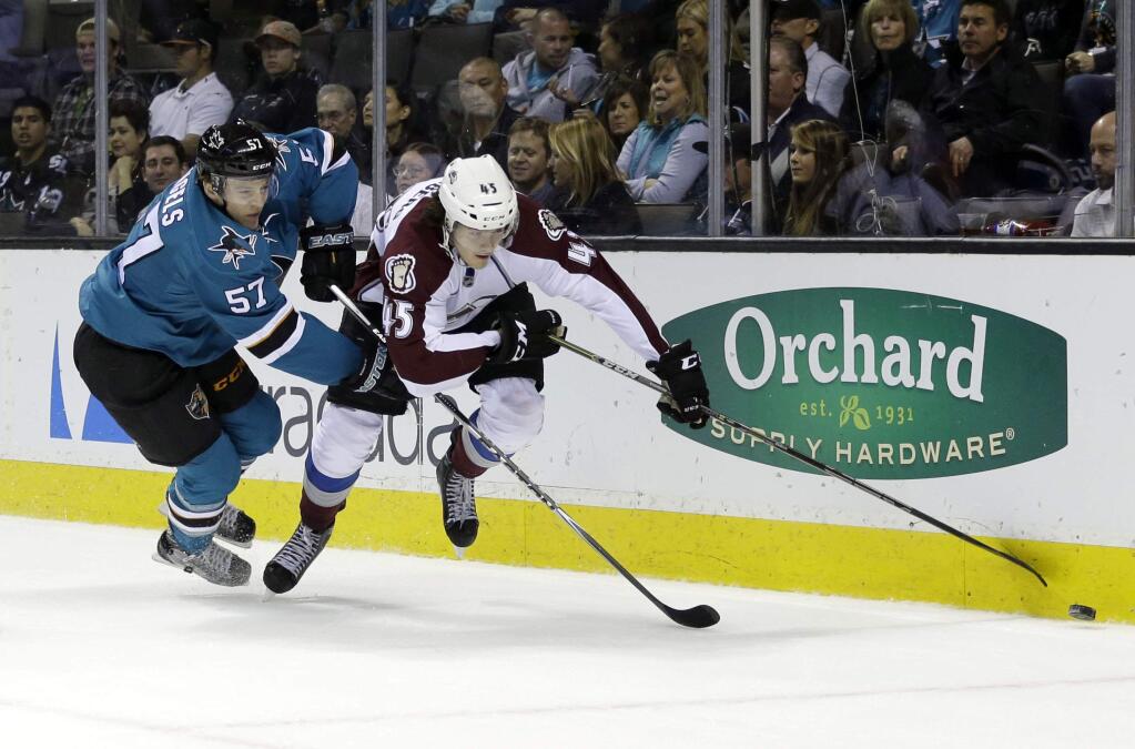 Colorado Avalanche's Dennis Everberg (45) reaches for the puck next to San Jose Sharks' Tommy Wingels (57) during the first period of an NHL hockey game Wednesday, April 1, 2015, in San Jose, Calif. (AP Photo/Marcio Jose Sanchez)