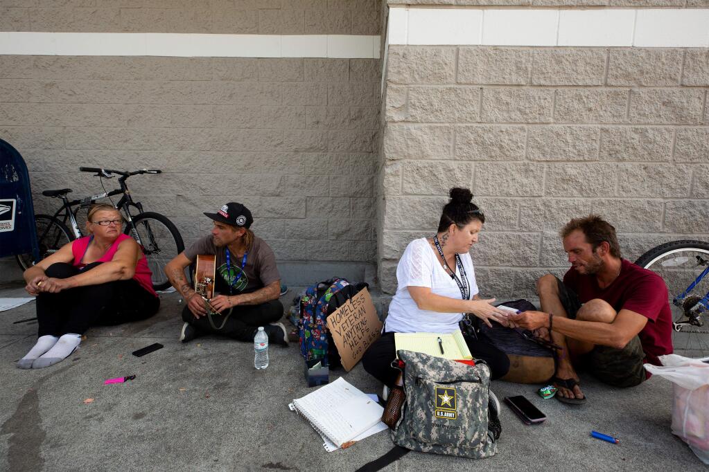 COTS homeless outreach specialist Cecily Kagy, second from right, encourages Jeffery Butler, right, to use some of the services COTS offers during a visit with him, Emily Morris-Jarboe, far left, and Joe Volavka where they congregate outside a Target store, in Rohnert Park, California, on Thursday, August 8, 2019. (Alvin Jornada / The Press Democrat)