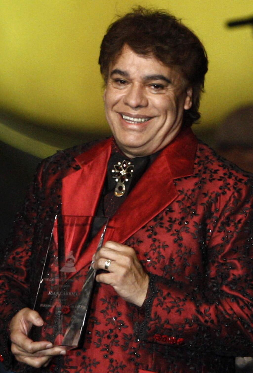 FILE - In this Nov. 4, 2009, file photo, Juan Gabriel holds the Latin Recording Academy Person of The Year award in Las Vegas. Representatives of Juan Gabriel have reported Sunday, Aug. 28, 2016, that he has died. Juan Gabriel was Mexico's leading singer-songwriter and top-selling artist with sales of more than 100 million albums. The statement says he died Sunday, but did not say where. (AP Photo/Matt Sayles, File)