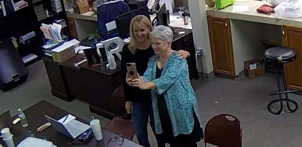 FILE - In this Jan. 7, 2021, image taken from Coffee County, Ga., security video, Cathy Latham, right, appears to take a selfie with a member of a computer forensics team inside the local elections office. Latham was the county Republican Party chair at the time. The computer forensics team was at the county elections office in Douglas, Ga., to make copies of voting equipment in an effort that documents show was arranged by attorney Sidney Powell and others allied with then-President Donald Trump. (Coffee County, Georgia via AP)