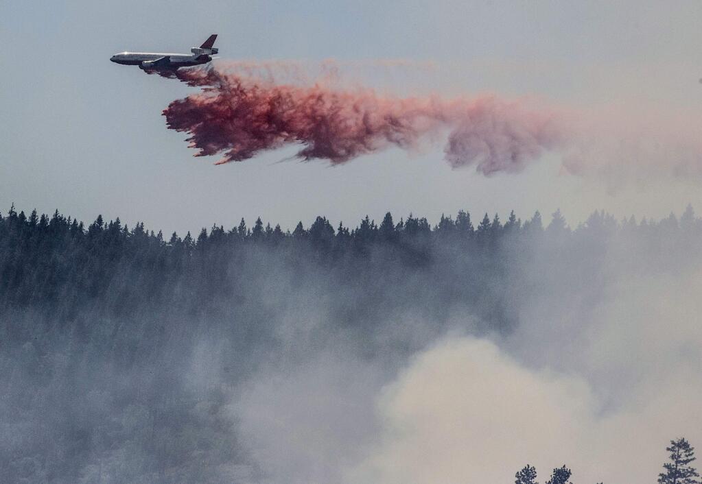 A plane drops fire retardant as firefighters battle a blaze near Yosemite National Park. (AL GOLUB / Associated Press)