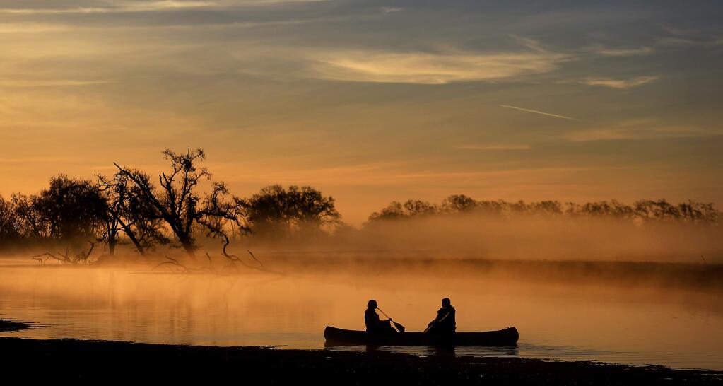 1/11/2014: B1: Britney Wehrfritz, left, and Steve Nemecek of Sebastopol paddle a canoe early Friday morning at the Laguna de Santa Rosa. Another foggy morning was expected in the North Coast region today, with spotty showers possible throughout the day, according to the AccuWeather forecasting service. Precipitation would be a welcome sight in rain-starved Northern California; Santa Rosa has seen just 2 inches of rainfall since the weather year began July 1, less than a tenth of the total at this time last year. PC: Britney Wehrfritz, left and Steve Nemecek of Sebastopol row take a canoe ride as a friend takes their engagement photo at the Laguna de Santa Rosa, early Friday morning Jan. 10, 2013. (Kent Porter / Press Democrat) 2014