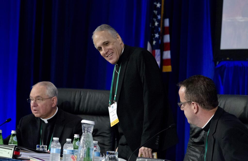 Cardinal Daniel DiNardo of the Archdiocese of Galveston-Houston, center, president of the United States Conference of Catholic Bishops, accompanied by Jose Gomez, archbishop of Los Angeles, left, and Rev. J. Brian Bransfield, right, get a sit before the morning prayer during the United States Conference of Catholic Bishops (USCCB), 2019 Spring meetings in Baltimore, Tuesday, Jun 11, 2019. (AP Photo/Jose Luis Magana)