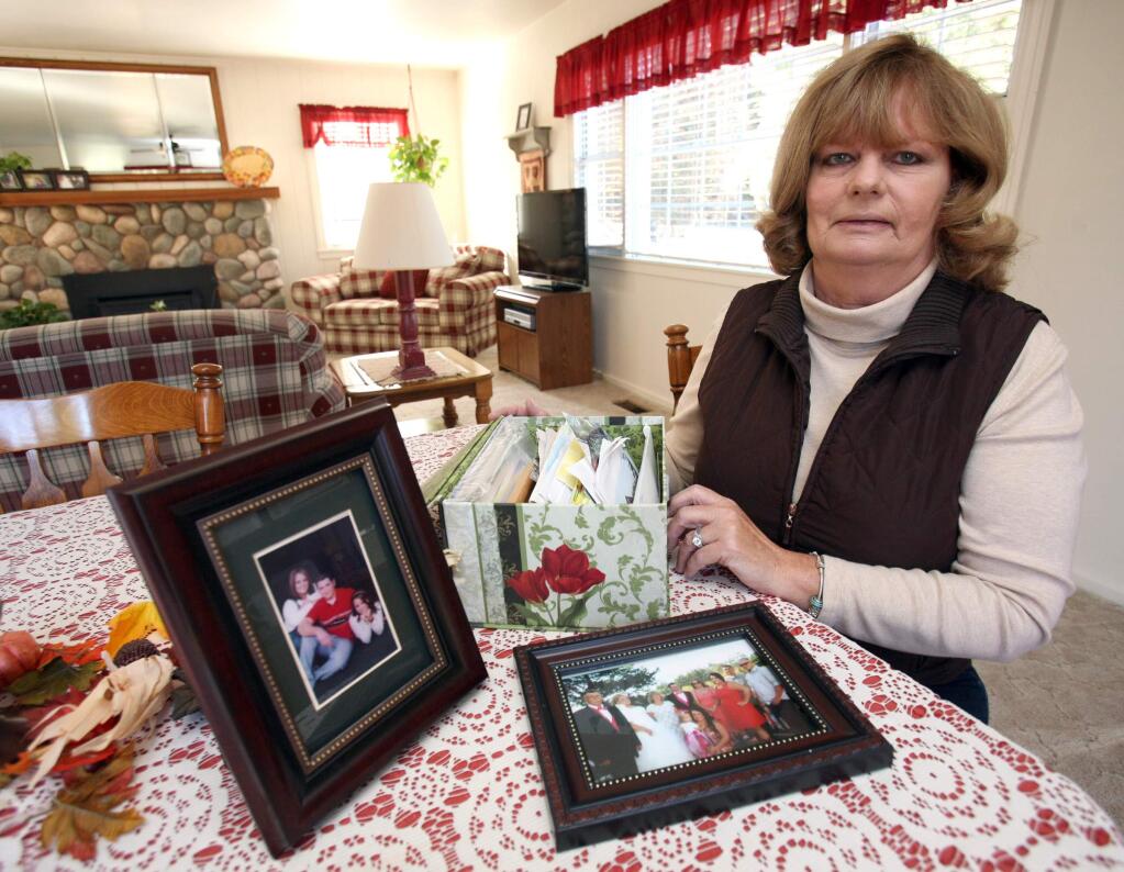 Janice MacKinnon with photos of her family and the Millard family in her home on Monday, November 24, 2014. The photo on the left is of Kalem Millard with his sisters Kalsey, left, and Koko shortly before he died and his family donated an organ that was received by Janice's son. Now almost ten years latter Janice was able to return the favor by donating a Kalem's father. Photo on the right is of both families together. The box is full of keepsakes that Janice has collected from the two families relationship over the years. (SCOTT MANCHESTER/ARGUS-COURIER STAFF)