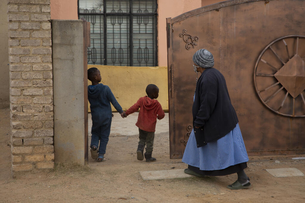 An elderly woman and children enter the property of the home of Gosiame Thamara Sithole in Tembisa, near Johannesburg Thursday June 10, 2021. South Africa is gripped by a mystery over if the woman, Sithole, has, as has been claimed, given birth to 10 babies in what would be a world-first case of decuplets.  The South African government said Thursday it is still trying to verify the claim. (AP Photo/Denis Farrell)