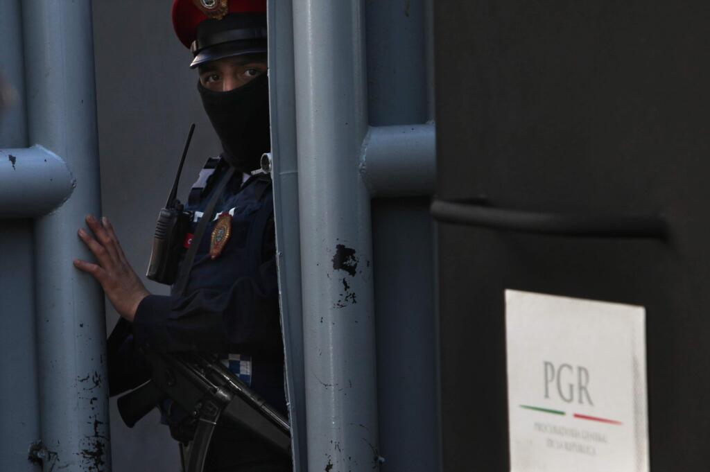 A masked federal police officer stands guard as part of increased security at the organized-crime division of Mexico's Attorney General Office where high profile detainees are sometimes held and shown to the press in Mexico City, Friday, Feb. 27, 2015. Leader of the Knights Templar cartel, Servando 'La Tuta' Gomez,' one of Mexico's most-wanted drug lords, was captured early Friday by federal police in the capital city of Morelia, according to a Mexican official. It could not be confirmed if Gomez was inside the building. (AP Photo/Marco Ugarte)
