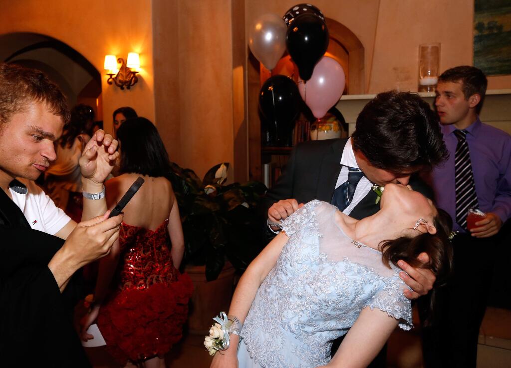 Eva Marie Sapper, right, leans back to share a kiss with her boyfriend Cole von Buchau after their friend Will Hansen, left, snapped a picture of them during prom night for special needs people at Mayacama Golf Club in Santa Rosa, California on Saturday, April 22, 2017. (Alvin Jornada / The Press Democrat)