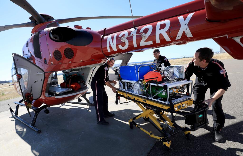 REACH Air Medical Services personnel, from left, flight nurse Parker Maloney, pilot Jeff Baker and flight paramedic David Hoytt, practice loading a portable incubator in one of the REACH helicopters at the Charles M. Schulz Sonoma County Airport, Friday, June 7, 2019. (Kent Porter / The Press Democrat) 2019