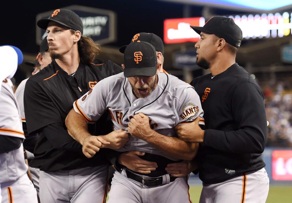 San Francisco Giants starting pitcher Madison Bumgarner, center, yells as he is pulled away by teammates after he and Los Angeles Dodgers' Yasiel Puig got into a scuffle that emptied both benches after Puig was thrown out at first by Bumgarner during the seventh inning of a baseball game, Monday, Sept. 19, 2016, in Los Angeles. (AP Photo/Mark J. Terrill)