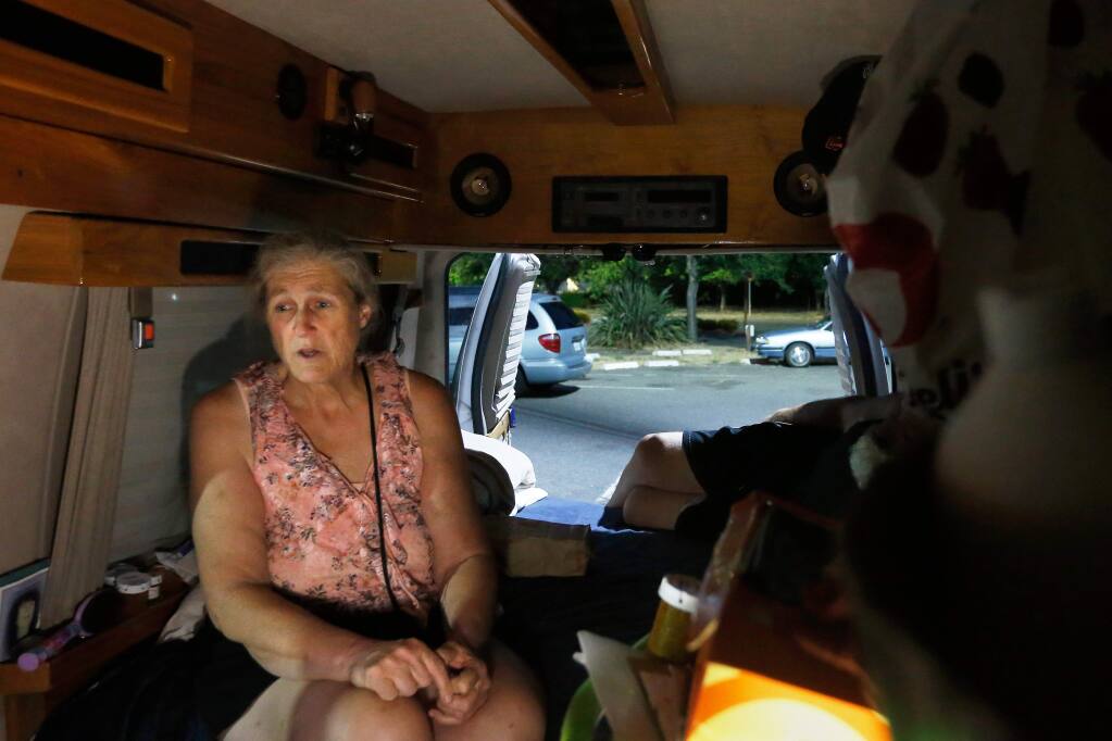 'We are not the face of homelessness that everyone sees. We dont need a handout; we just need a hand up, a safe place to get back on our feet again,' says Marilee Diehl referring to the safe parking program. Illuminated by a camping lantern, Marilee sits in her van at one of the designated safe parking lots for the homeless in Santa Rosa, California, on Saturday, July 15, 2017. (Alvin Jornada / The Press Democrat)