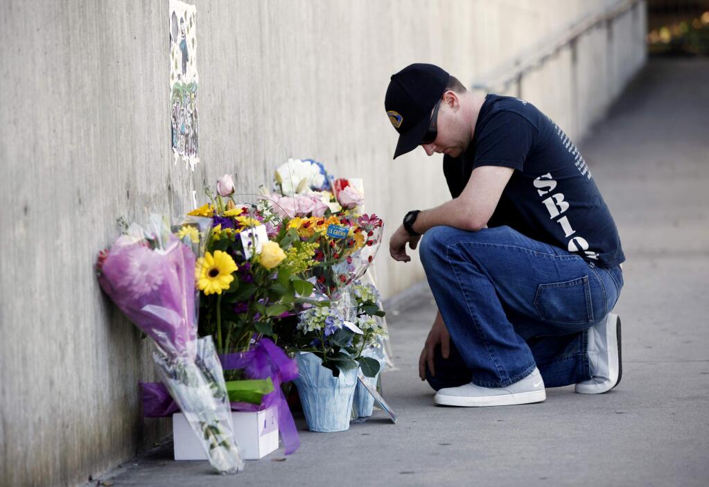 Officer Brandon Monlux, of the San Jose Police Department, pauses after dropping off flowers in front of a memorial for police officer, Michael Johnson, in front of the San Jose Police Department headquarters in San Jose, Calif., Wednesday, March 25, 2015. A man threatening to commit suicide unleashed a barrage of gunfire on Northern California officers called to check on him, killing Johnson, a 14-year veteran of the San Jose Police Department on Tuesday. (AP Photo/San Jose Mercury News, Gary Reyes)