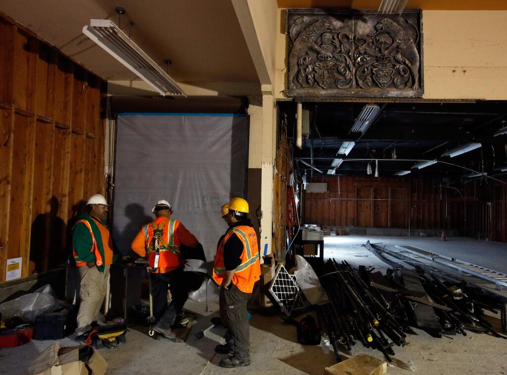 A leftover piece of facade, upper right, remains on a wall in what was previously the Burbank Auditorium prop shop, with construction workers punching out at the end of their day of renovating the nearly 80-year-old building at Santa Rosa Junior College in Santa Rosa, California, on Wednesday, January 17, 2018. (Alvin Jornada / The Press Democrat)