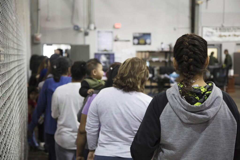 In this photo provided by U.S. Customs and Border Protection, people who've been taken into custody related to cases of illegal entry into the United States, stand in line at a facility in McAllen, Texas, Sunday, June 17, 2018. (U.S. Customs and Border Protection's Rio Grande Valley Sector via AP)