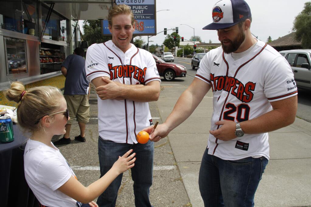 Bill Hoban/Index-TribuneStompers Kevin Farley, center, and Tom Lyons, right, sign a ball for 9-year-old Alexandra Sebastiani during the Stompers' inaugural Fan Fest on April 22. The Stompers open their season June 2, at Pittsburg, and have their home opener Tuesday, June 13.