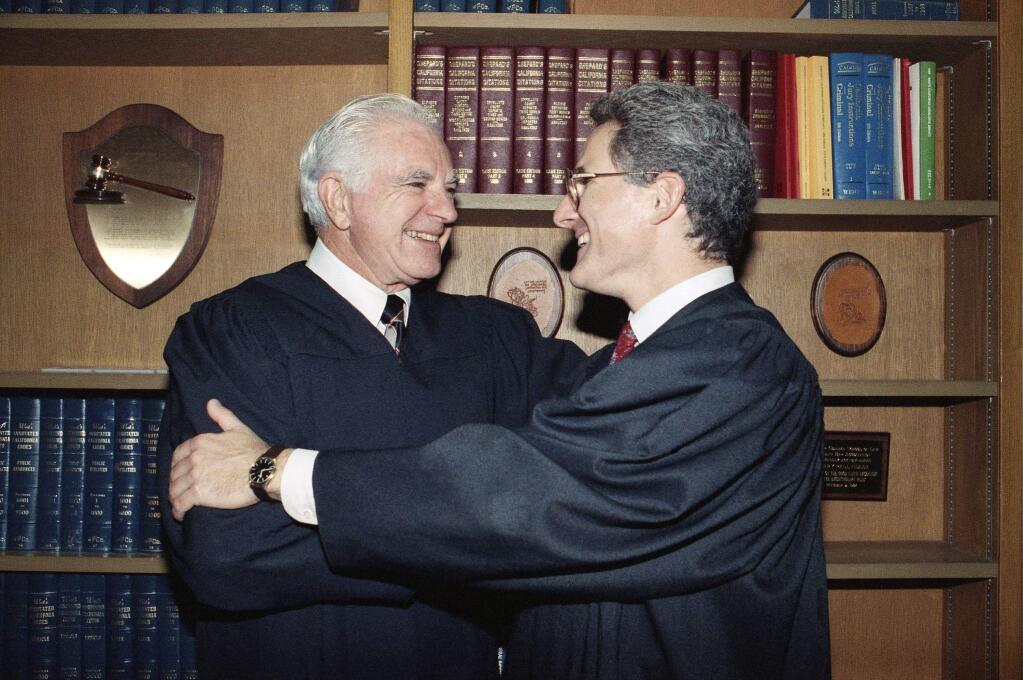 FILE - In this Friday, Oct. 13, 1989, file photo, retired Judge Joseph A. Wapner of TV's 'The People's Court' congratulates his son, Judge Frederick N. Wapner, right, as he was enrobed as a Municipal Court judge in Los Angeles. Wapner, who presided over 'The People's Court' with steady force during the heyday of the reality courtroom show, has died. Wapner died at home in his sleep Sunday, Feb. 26, 2017, according to his son, David Wapner. (AP Photo/Nick Ut, File)