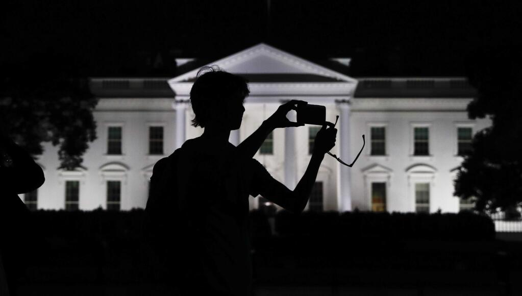 FILE - In this Aug. 25, 2017, file photo, a tourist takes a photo from Pennsylvania Avenue of the illuminated White House in Washington. The White House is embarking on a major campaign to turn public opinion against the nation's largely family-based immigration system ahead of an all-out push next year to move toward a more merit-based structure. (AP Photo/Carolyn Kaster, File)