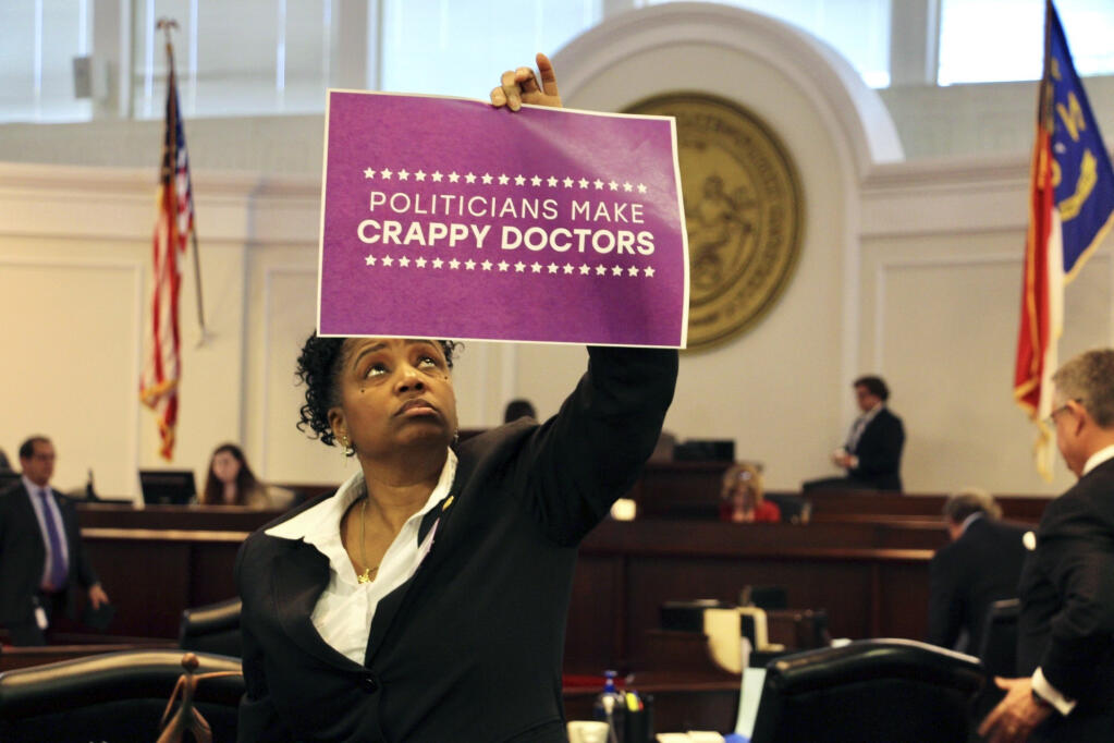 North Carolina state Sen. Kandie Smith, a Pitt County Democrat, holds up a sign that reads "Politicians Make Crappy Doctors" on the Senate floor in Raleigh, N.C., after the chamber voted to approve new abortion restrictions, Thursday, May 4, 2023. (AP Photo/Hannah Schoenbaum)