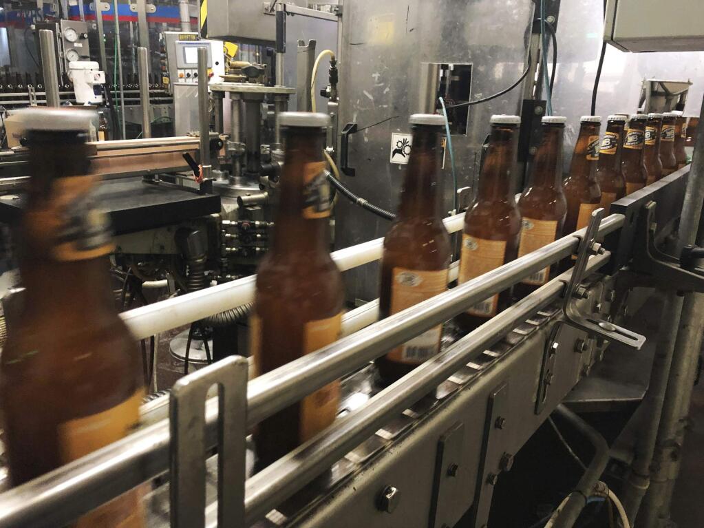 FILE - In this Jan. 14, 2019, file photo, bottles, freshly filled with beer, move on a belt at Lakefront Brewery in Milwaukee. At the Strange Brew Festival in Reno, Nev., in May 2019, visitors could sample a peanut butter and pickle pilsner, a tamale lager and a smoked carrot stout. As craft breweries have boomed, competition for attention has intensified. (AP Photo/Carrie Antlfinger, File)