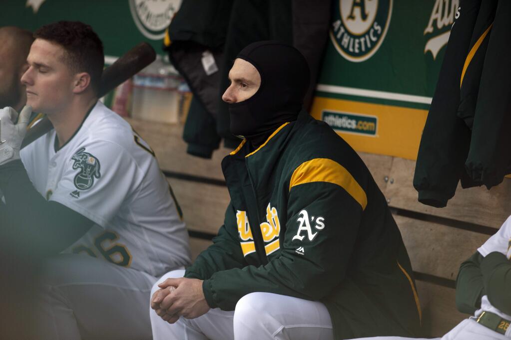 Oakland Athletics left fielder Mark Canha wears a face mask against the cool temperatures during the first inning of the team's game against the Seattle Mariners, Tuesday, May 22, 2018, in Oakland. (AP Photo/D. Ross Cameron)