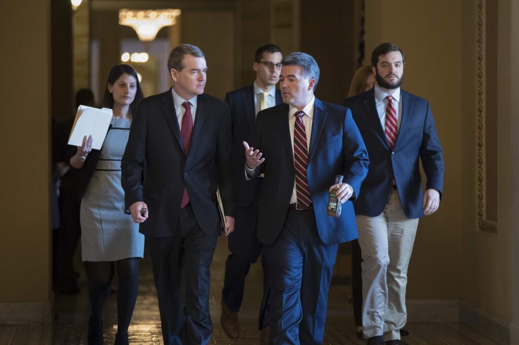 Sen. Michael Bennet, D-Colo., left, and Sen. Cory Gardner, R-Colo., head to the chamber for a series of procedural votes on a bipartisan immigration deal, at the Capitol in Washington, Thursday, Feb. 15, 2018. President Donald Trump would veto a bipartisan Senate compromise that would help young 'Dreamer' immigrants and build his coveted border wall, the White House threatened. (AP Photo/J. Scott Applewhite)