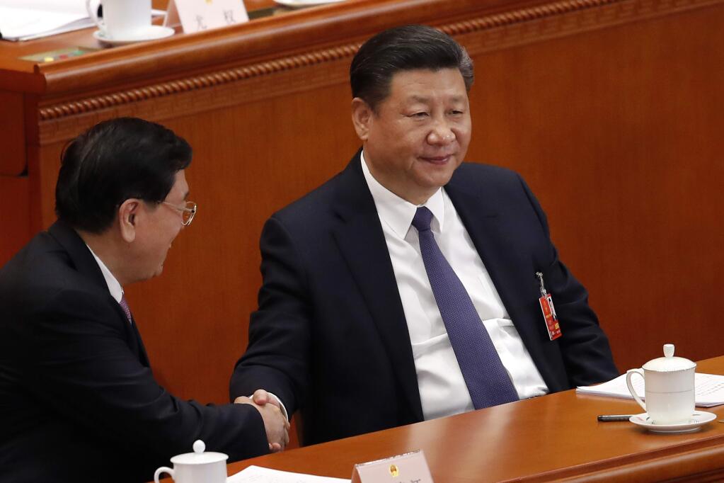 Chinese President Xi Jinping, right, shakes hands with National People's Congress Chairman Zhang Dejiang during a plenary session of the National People's Congress at the Great Hall of the People in Beijing, Sunday, March 11, 2018. China's rubber-stamp lawmakers on Sunday passed a historic constitutional amendment abolishing presidential term limits that will enable Xi to rule indefinitely. (AP Photo/Andy Wong)